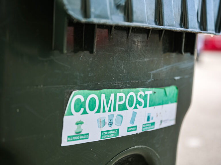 Compost sign with symbols and text for food, compostable containers, and other items.