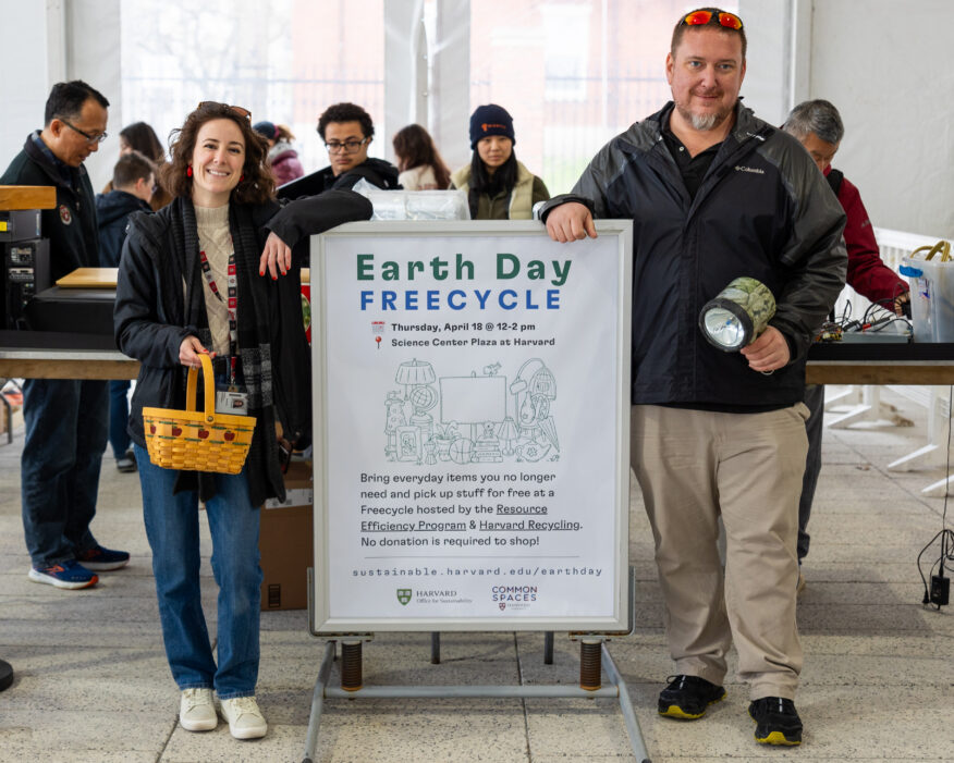 Harvard sustainability staff stand next to a poster that says "Earth Day Freecycle."